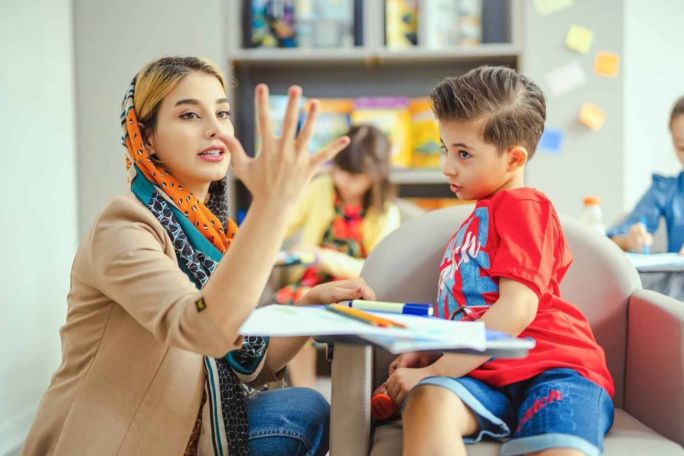 معلمة تشرح لطالب داخل فصل ملوّن